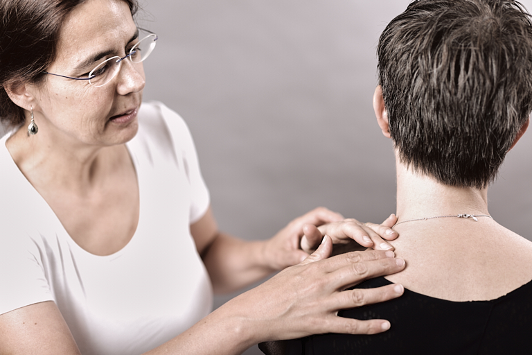 Massagetherapeutin untersucht Verspannungen an der Schulter